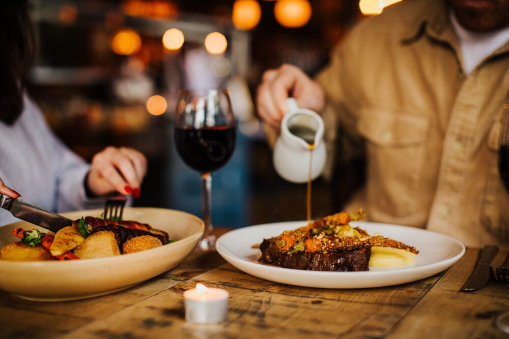 A glass of red wine accompanied by delicious pub food at The Hanbury Pub, creating a perfect pairing